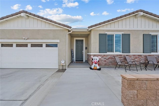 ranch-style home with a tile roof, an attached garage, driveway, and stucco siding