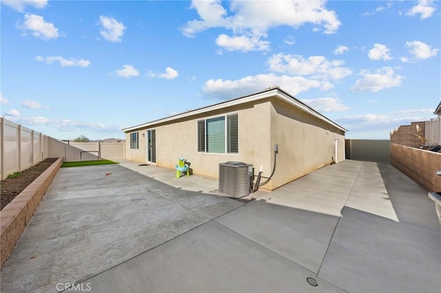 back of house featuring a patio area, a fenced backyard, central AC, and stucco siding