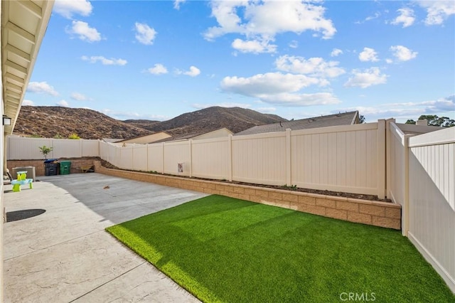 view of yard with a patio area, a mountain view, and a fenced backyard