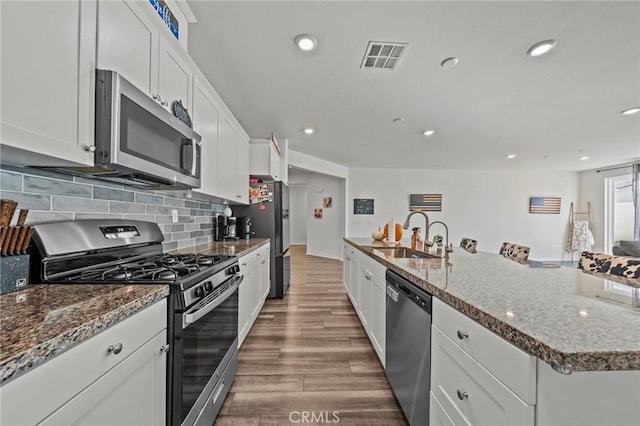 kitchen with tasteful backsplash, white cabinetry, stainless steel appliances, and a sink