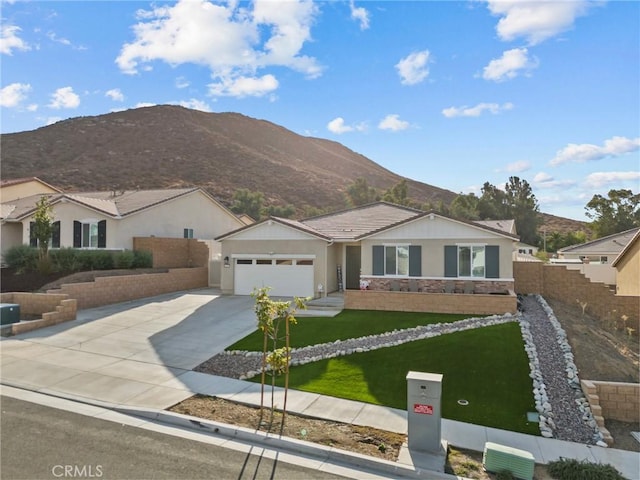 single story home with fence, driveway, an attached garage, a front lawn, and a mountain view