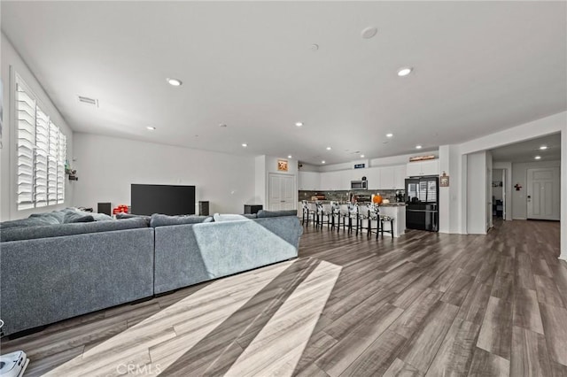 living area featuring recessed lighting, dark wood-style floors, and visible vents