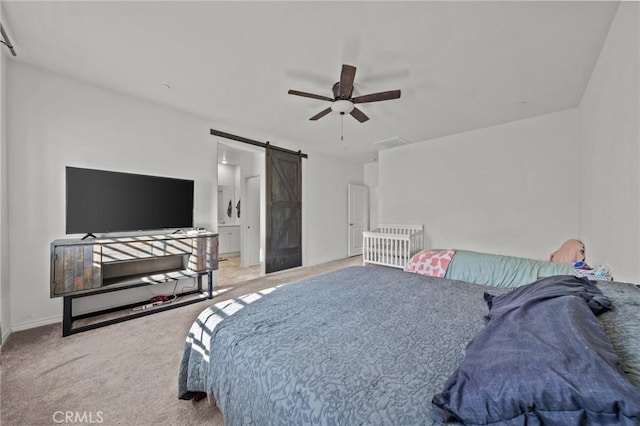 carpeted bedroom featuring a barn door, a ceiling fan, and baseboards