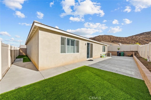 rear view of property with stucco siding, a lawn, a patio, a fenced backyard, and cooling unit