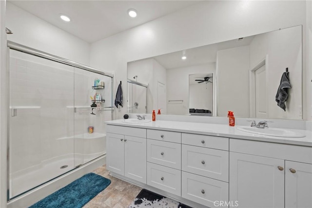 full bathroom featuring double vanity, a stall shower, and a sink