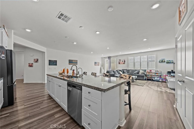 kitchen featuring visible vents, a sink, stainless steel dishwasher, white cabinetry, and freestanding refrigerator