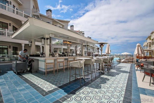 view of patio with a water view, exterior bar, and a balcony