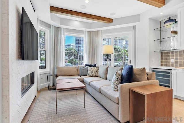 living room featuring a wealth of natural light, beam ceiling, light hardwood / wood-style flooring, and a fireplace