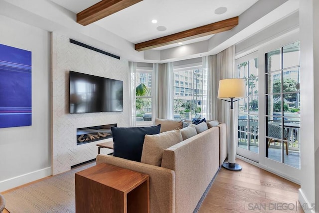 living room with light hardwood / wood-style floors, beamed ceiling, and a fireplace