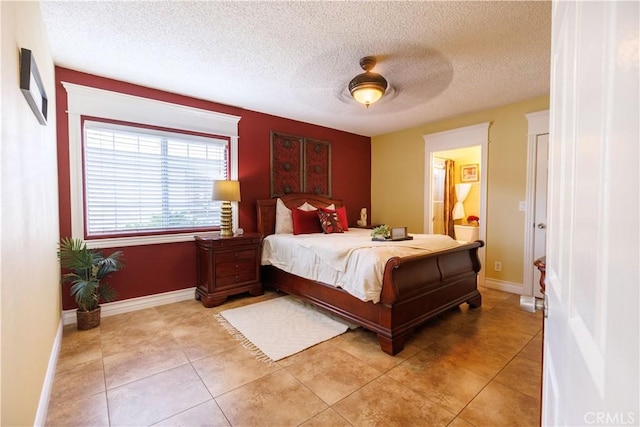 bedroom with ceiling fan, light tile patterned flooring, and a textured ceiling