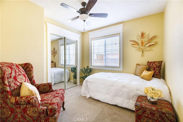 bedroom featuring a textured ceiling, carpet floors, a closet, and ceiling fan