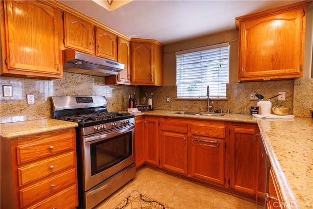 kitchen with stainless steel gas stove, sink, light stone counters, decorative backsplash, and light tile patterned floors