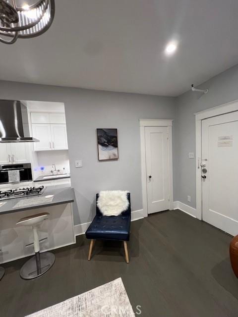 interior space with dark hardwood / wood-style flooring, white cabinetry, stainless steel gas cooktop, and wall chimney exhaust hood