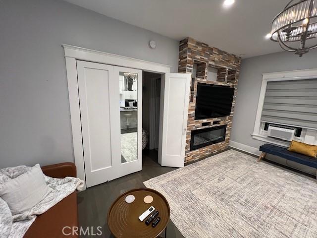 living room with french doors, a stone fireplace, dark hardwood / wood-style floors, a notable chandelier, and cooling unit