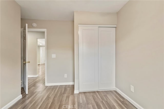 unfurnished bedroom with a closet and light wood-type flooring