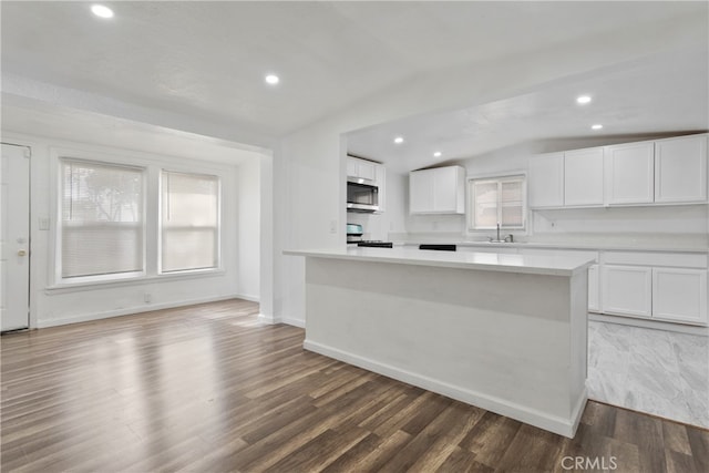 kitchen featuring a wealth of natural light, lofted ceiling, white cabinetry, and dark hardwood / wood-style flooring