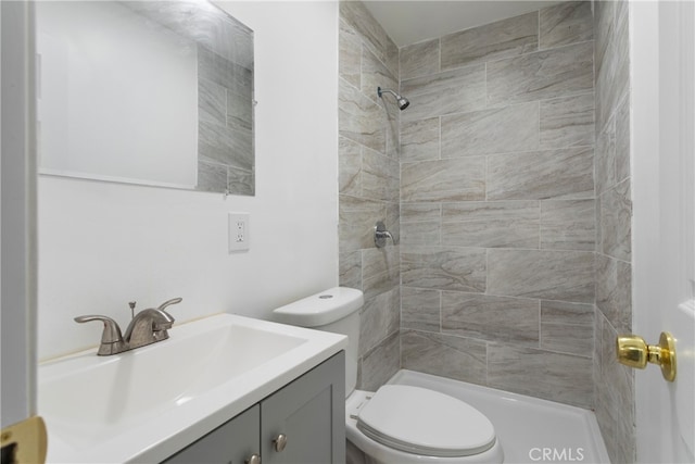 bathroom with vanity, toilet, and a tile shower