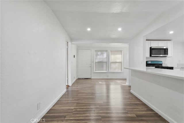 interior space with black range, white cabinets, and dark hardwood / wood-style flooring