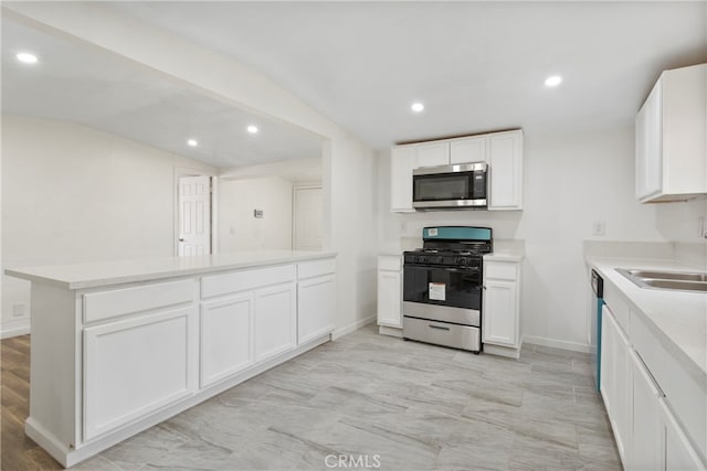 kitchen featuring sink, kitchen peninsula, stainless steel appliances, lofted ceiling, and white cabinets