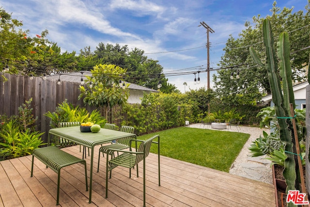 wooden terrace with a fire pit and a lawn