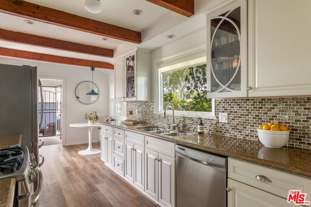 kitchen featuring dark stone counters, light hardwood / wood-style flooring, decorative backsplash, beam ceiling, and stainless steel appliances