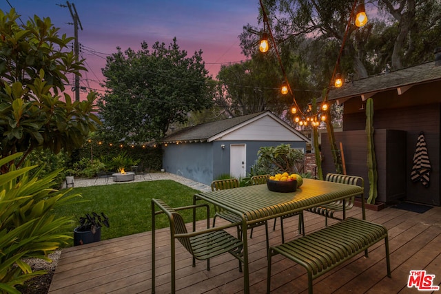 deck at dusk with an outbuilding and a lawn