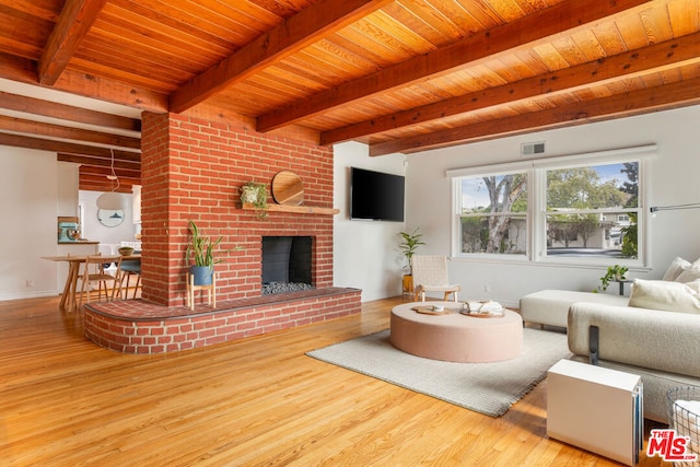 living room with beam ceiling, hardwood / wood-style floors, wooden ceiling, and a brick fireplace