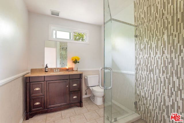 bathroom with tile patterned floors, vanity, toilet, and a shower with door