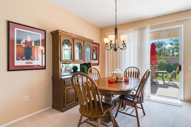 dining space with light carpet and a chandelier