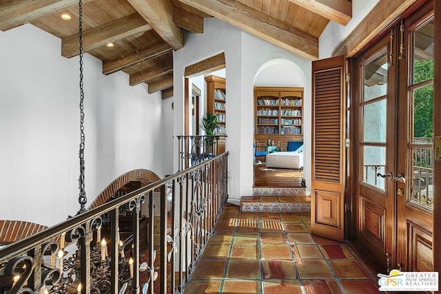 interior space featuring lofted ceiling with beams, dark tile patterned floors, a wealth of natural light, and wood ceiling