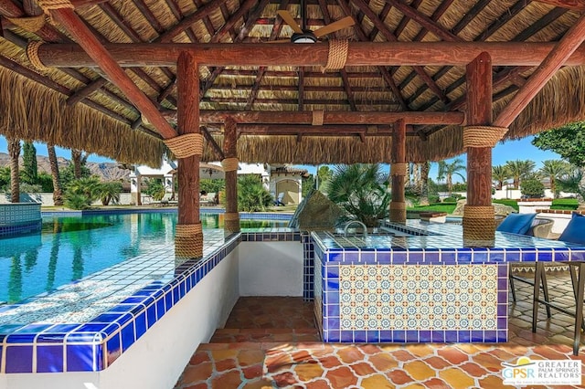 view of patio featuring a bar, ceiling fan, exterior kitchen, and a gazebo