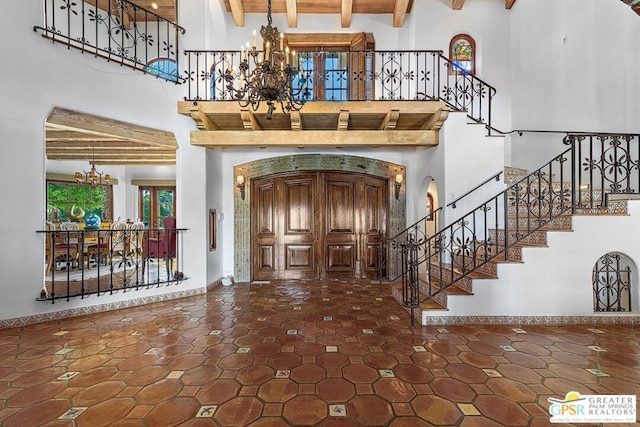 entryway with a notable chandelier, beam ceiling, and a towering ceiling