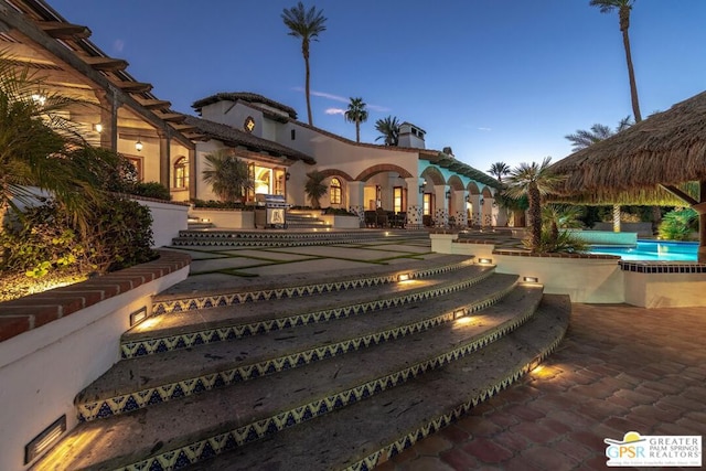 pool at dusk featuring a grill and a patio area