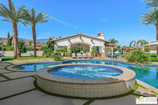 view of pool featuring an in ground hot tub, a mountain view, and a patio