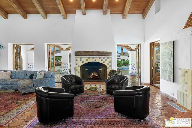 tiled living room featuring a fireplace, a towering ceiling, wooden ceiling, and beamed ceiling