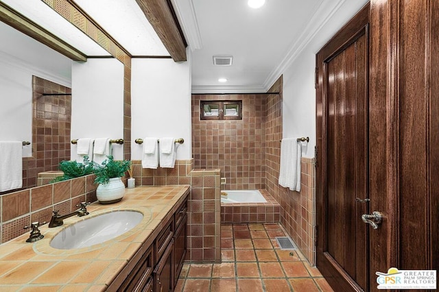 bathroom featuring tile patterned flooring, a relaxing tiled tub, crown molding, vanity, and tile walls