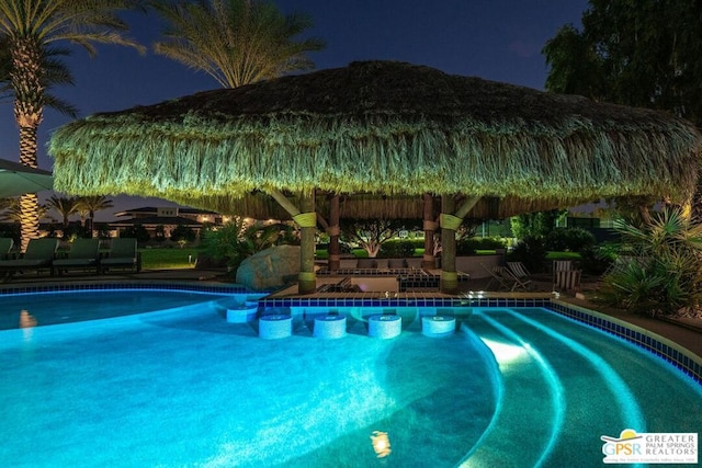 pool at twilight featuring a gazebo