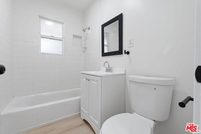 full bathroom with hardwood / wood-style floors, vanity, toilet, and tiled shower / bath