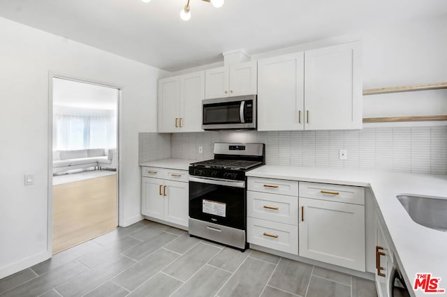 kitchen with appliances with stainless steel finishes, tasteful backsplash, sink, light hardwood / wood-style floors, and white cabinetry