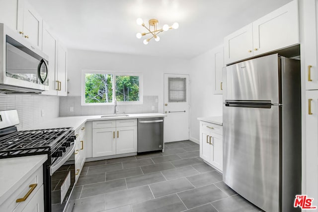 kitchen with an inviting chandelier, white cabinets, sink, decorative backsplash, and appliances with stainless steel finishes