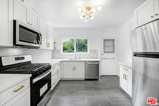 kitchen featuring decorative backsplash, white cabinets, a notable chandelier, and appliances with stainless steel finishes