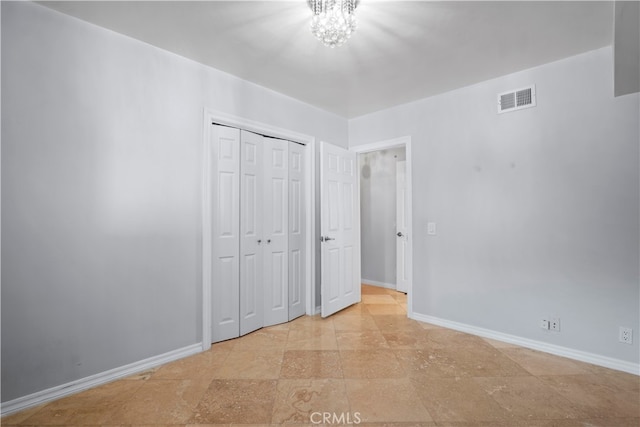 unfurnished bedroom featuring a closet and an inviting chandelier