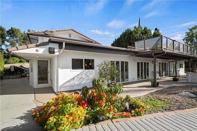 back of property featuring a balcony and a patio