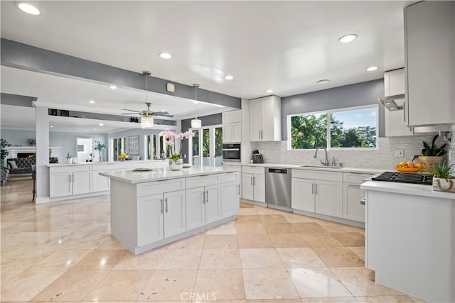 kitchen with decorative backsplash, white cabinetry, stainless steel appliances, sink, and a center island