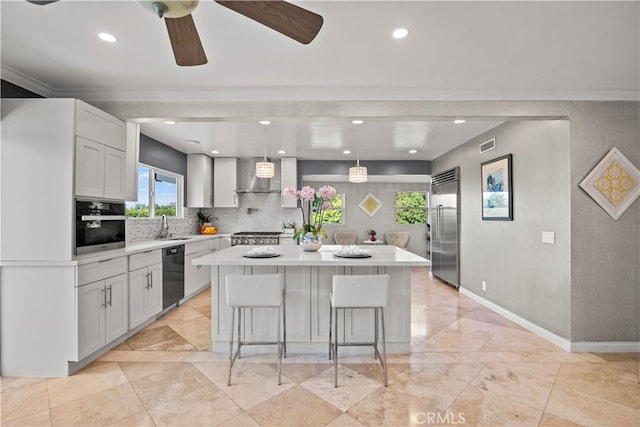 kitchen with wall chimney range hood, appliances with stainless steel finishes, a center island, and white cabinets