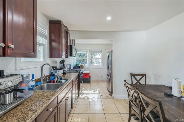 kitchen with sink, light tile patterned flooring, dark stone counters, and appliances with stainless steel finishes