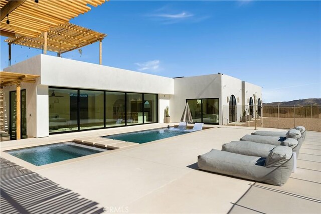 back of house featuring a swimming pool with hot tub and a patio area