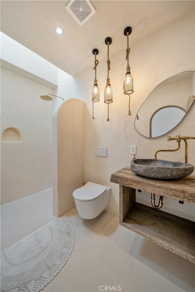 bathroom with concrete flooring, a shower, toilet, and sink