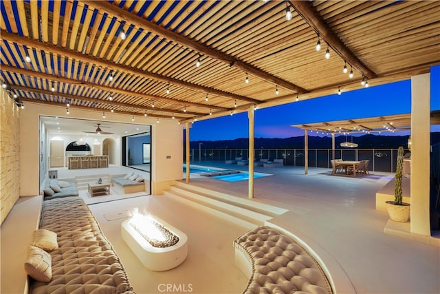 patio terrace at dusk featuring a fire pit, ceiling fan, and a fenced in pool