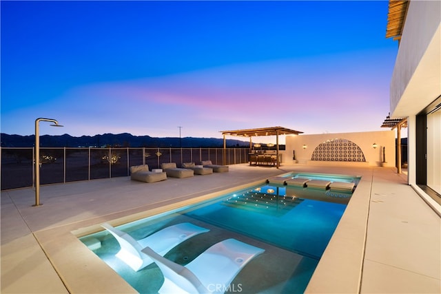 pool at dusk with an in ground hot tub and a patio